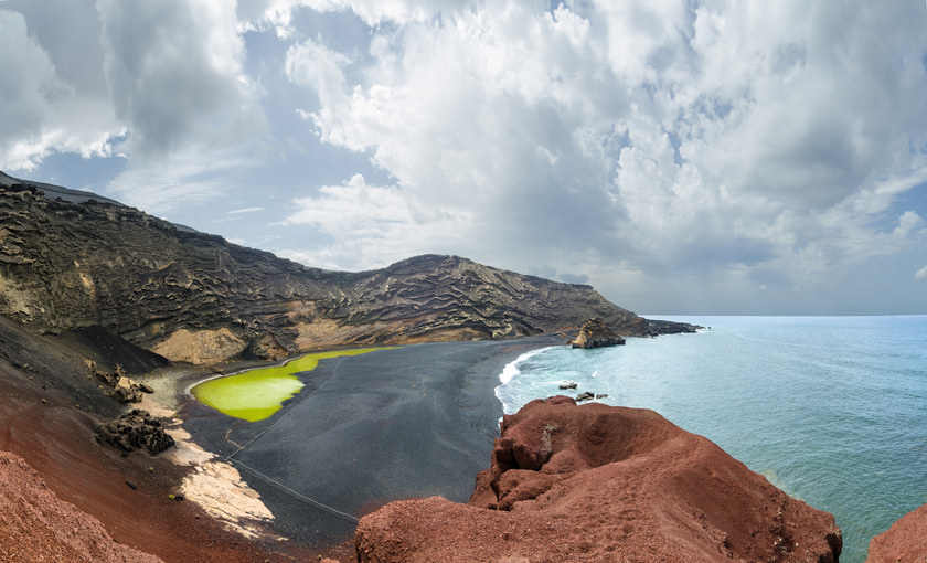 Zwart strand met een groen meer op Lanzarote
